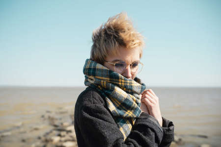 Young female in glasses warming herself on a beachの写真素材
