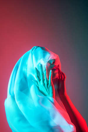 Studio portrait of woman with her face covered in neon blue and red lightningの写真素材