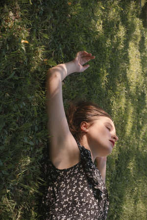 Young woman in black dress lying on green grassの写真素材