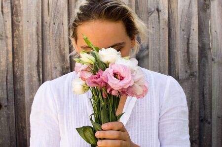 Young woman in white top holding pink and white flowers
