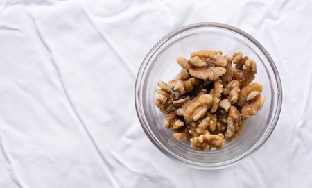 High angle view of walnuts in glass dish on white tableclothの写真素材