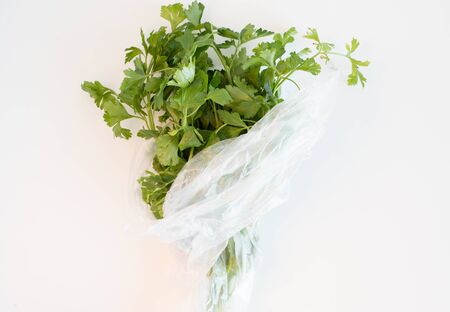 High angle view of flat leaf parsley in a plastic bag on a white tableの写真素材