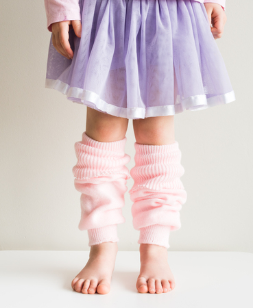 Little girl standing in soft pink knitted legwarmers and purple tutu (cropped)の写真素材