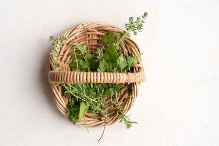 High angle view of thyme and parsley in small wicker basket on limestone background (selective focus)の写真素材