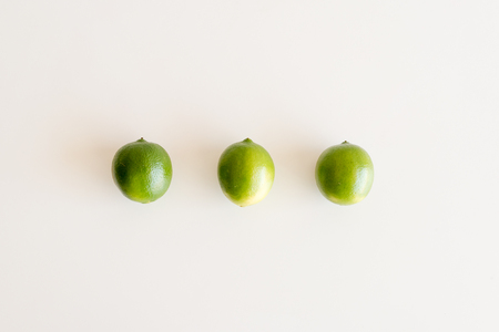 High angle view of three green limes on white tableの写真素材