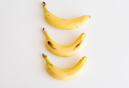High angle view of three bananas arranged vertically on white tableの写真素材