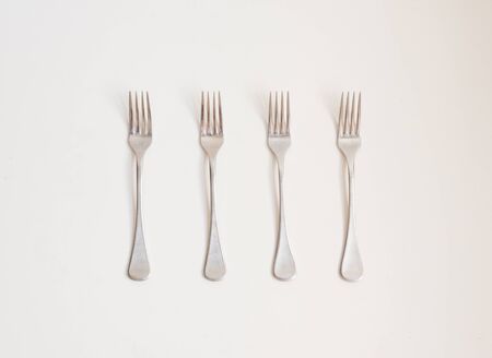 Food background - high angle view of four forks in a row on a white tableの写真素材