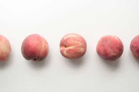 High angle view of five white peaches arranged in a row on tableの写真素材