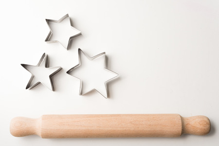 High angle view of rolling pin and cookie cutter stars on white table with copy space to rightの写真素材