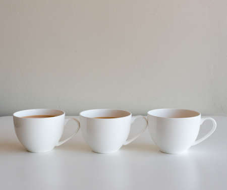 Three cups of white tea on a table against neutral wall background (selective focus)の写真素材