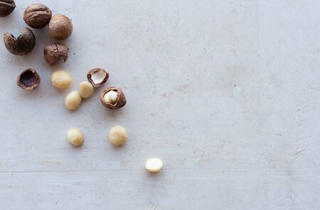 High angle close up view of whole and cracked macadamia nuts scattered on cream limestone background with copyspace (selective focus)の写真素材