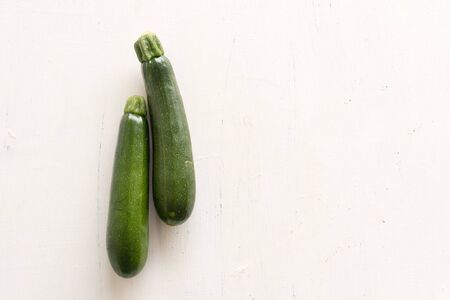 High angle view of two zucchini on rustic white background with copy space to rightの写真素材