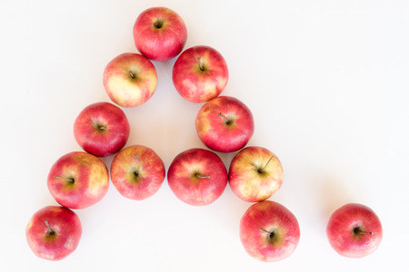 High angle view of organic pink lady apples arranged to write "A." on white backgroundの写真素材