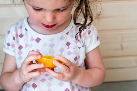High angle view of little girl holding orange piece (selective focus)の写真素材