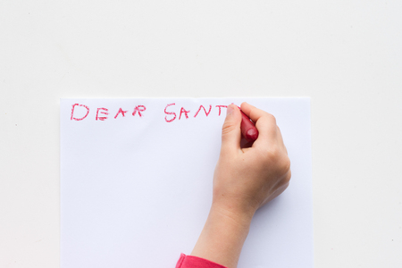 High angle view of child's hand writing letter to Santa in red crayonの写真素材