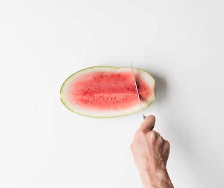 HIgh angle cropped view of woman's hand cutting watermelon slicesの写真素材