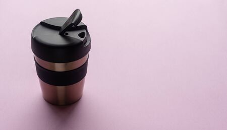 Close up of reusable coffee cup on pink background from above