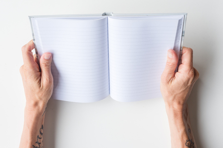 High angle view of woman's hands holding  blank journal on white tableの写真素材