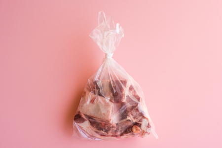 Directly above view of meat in plastic bag on pink backgroundの写真素材