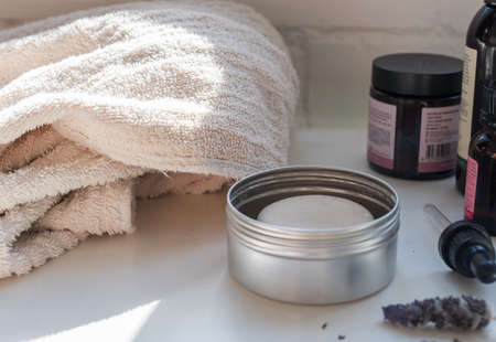 Closeup of beige towel with self care items on table including lotion bar, dropper and bottles (selective focus)の写真素材
