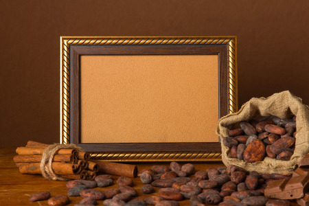 Frame decorated with cocoa beans and chocolate on a wooden backgroundの写真素材