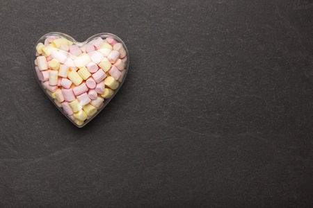 Marshmallow in a container in the form of a heart on a stone background. Sweets for Valentine's Day.の写真素材