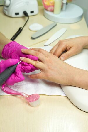 Close Up shot of a woman in a nail salon receiving a manicure . Woman getting nail manicure by manicure machineの写真素材
