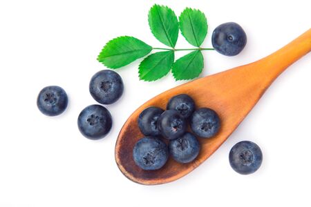 Fresh blueberries in a wooden spoons on a white surface of a tableの写真素材