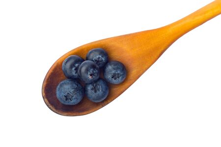 Fresh blueberries in a wooden spoons on a white surface of a table. With pathの写真素材