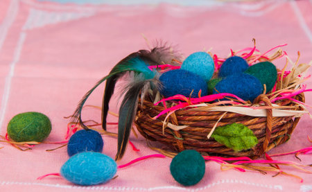 Woolen eggs in the basket on the pink background