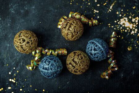 New Years Christmas gold and blue balls on a dark background with scattered sequinsの写真素材