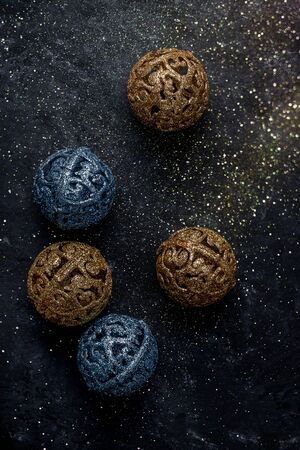 New Years Christmas gold and blue balls on a dark background with scattered sequinsの写真素材