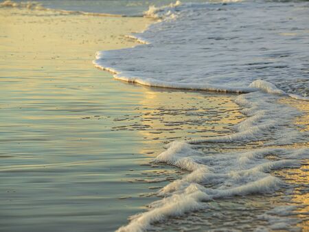 Sunset on the ocean, surf on the beach, beautiful reflection in the water, close upの写真素材