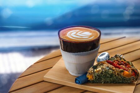 A cup of coffee with a piece of veggie pie on a table, blurred backgroundの写真素材