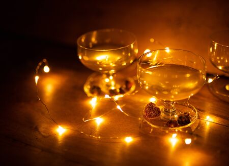 Two cocktail glasses with berries and lights glowing on wooden background still lifeの写真素材