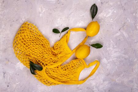 Lemons in yellow string mesh reusable bag on the tableの写真素材