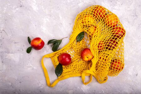 Nectarines in yellow string mesh reusable bag on the tableの写真素材