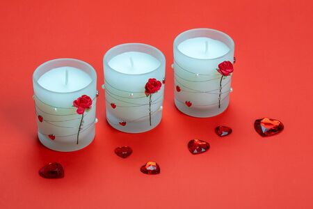 Aroma candles decorated with roses and hearts on red background. Valentines day.の写真素材