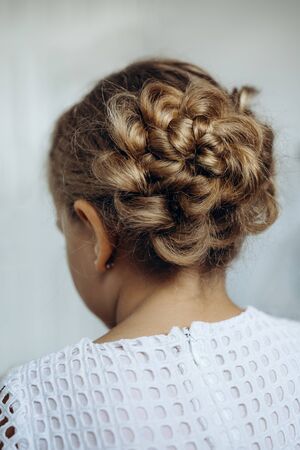 Festive hairstyle from braid on a child girl with long hair, back view.の写真素材