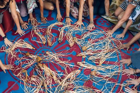 Different ages and nationalities females hands around their weaving craft on the carpet after the...