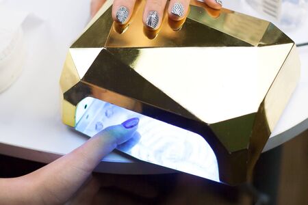 Close Up shot of a woman in a nail salon receiving a manicure by a beautician. Fingernails with...