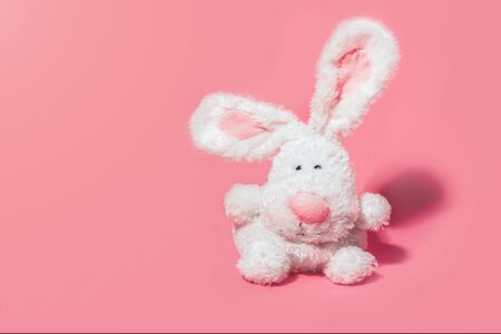 Adorable stuffed bunny on pink background with copy space. Minimal Easter concept.の写真素材