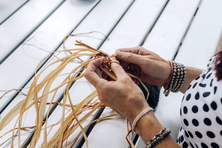 Female weaving basket on the craft workshop. Hands holding the craftwork, close up shot.の写真素材