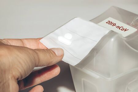Womans hand taking a pack with pills from the box. Novel coronavirus disease named 2019-nCoV written...