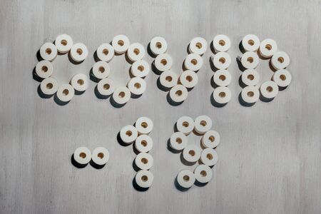 Title Covid-19 made with rolls of toilet paper on white wooden background. Concept of crisis,...