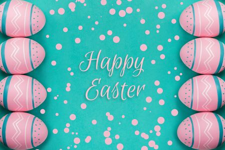 Pink colored decorated eggs on the neo-mint background with confetti and sign Happy Easter. Easter...