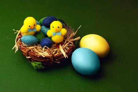 Colorful gypsum easter eggs on green background with basket and chicken toys.の写真素材