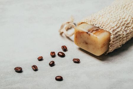 Piece of soap in natural bag with coffee beans on rustic grey background. Health and beauty concept.の写真素材