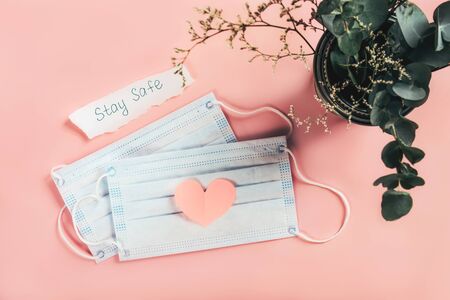 COVID-19. Facial mask with a piece of paper with a sign stay safe and a cut-out heart shape on a...