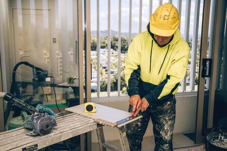Man hands marking tile to be cut. Laying ceramic floor tiles, home renovation.の写真素材